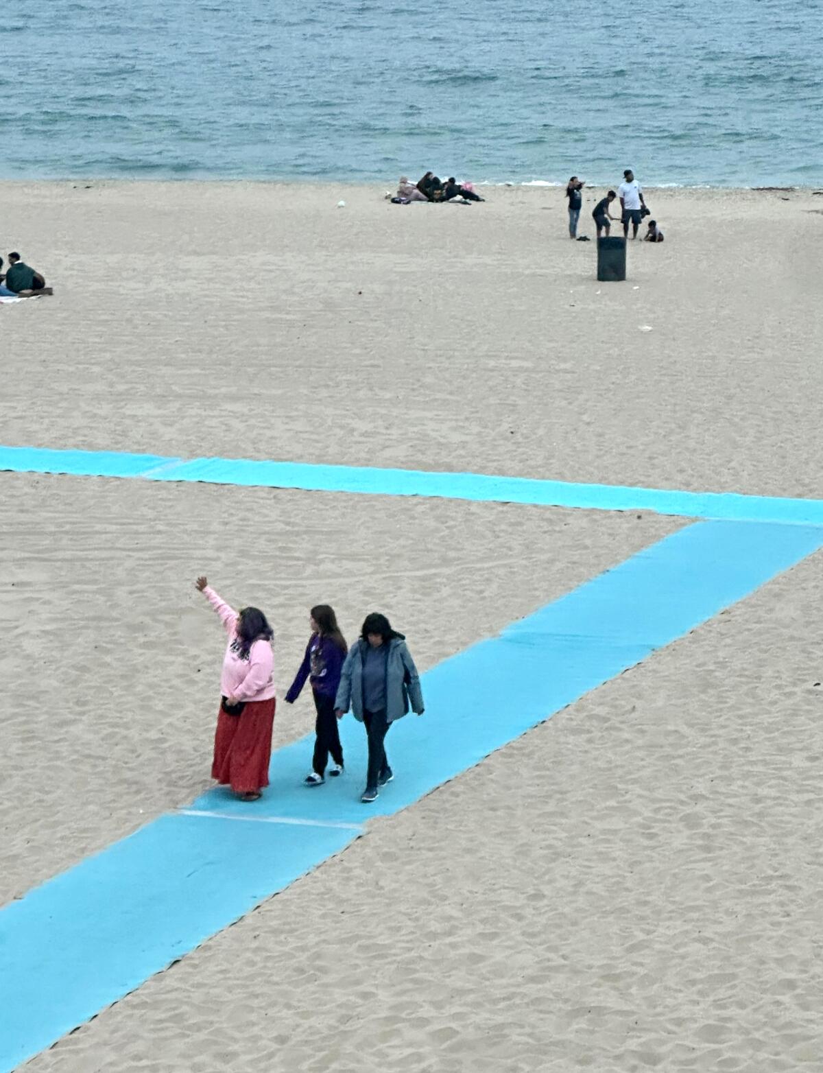 People walk along a beach mat.