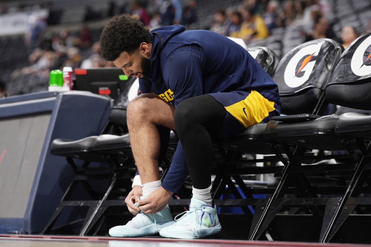Injured Denver Nuggets guard Jamal Murray adjusts his shoe while practicing before the team's NBA basketball game against the Memphis Grizzlies on Thursday, April 7, 2022, in Denver. (AP Photo/David Zalubowski)