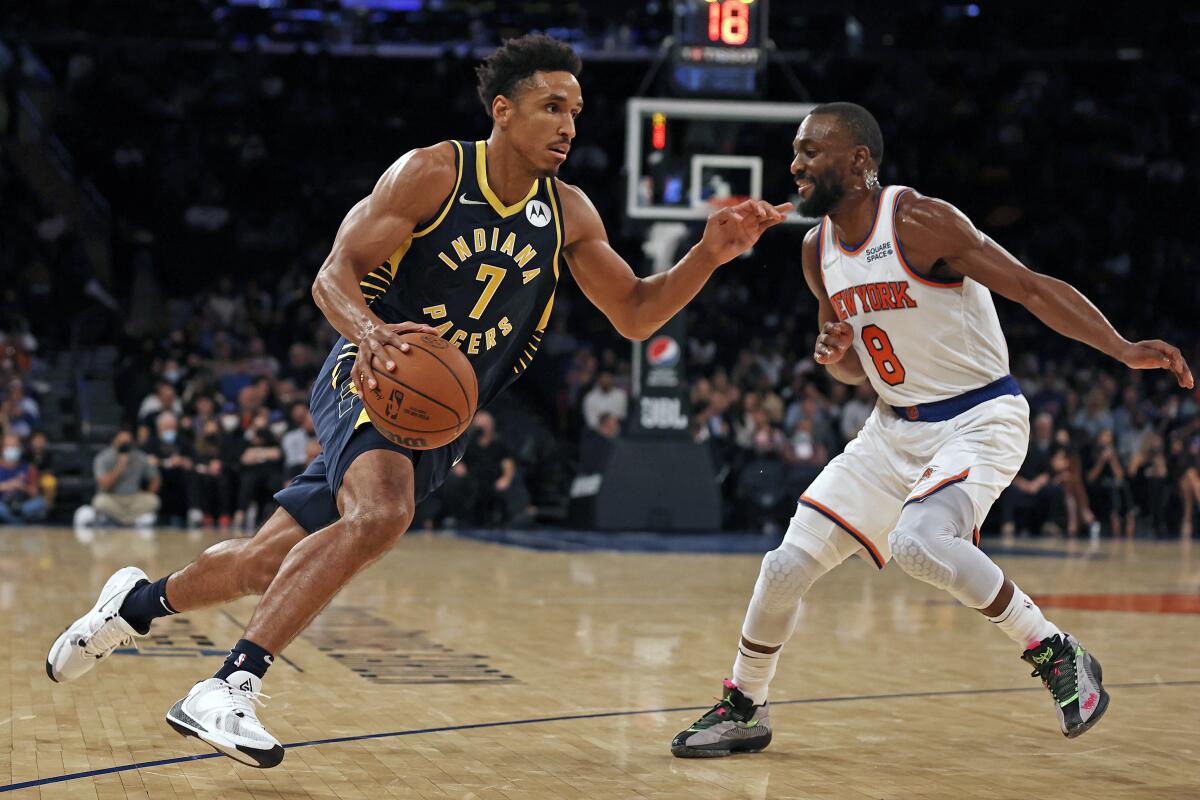 Indiana Pacers guard Malcolm Brogdon (7) drives to the basket past New York Knicks guard Kemba Walker (8) during the first half of a preseason NBA basketball game Tuesday, Oct. 5, 2021, in New York. (AP Photo/Adam Hunger)