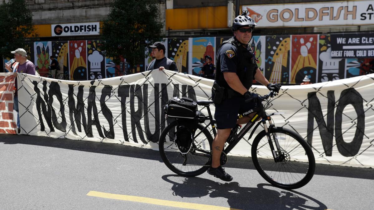 Immigrant rights activists hold up a fabric wall protesting Republican presidential candidate Donald Trump as law enforcement officers look on in Cleveland.