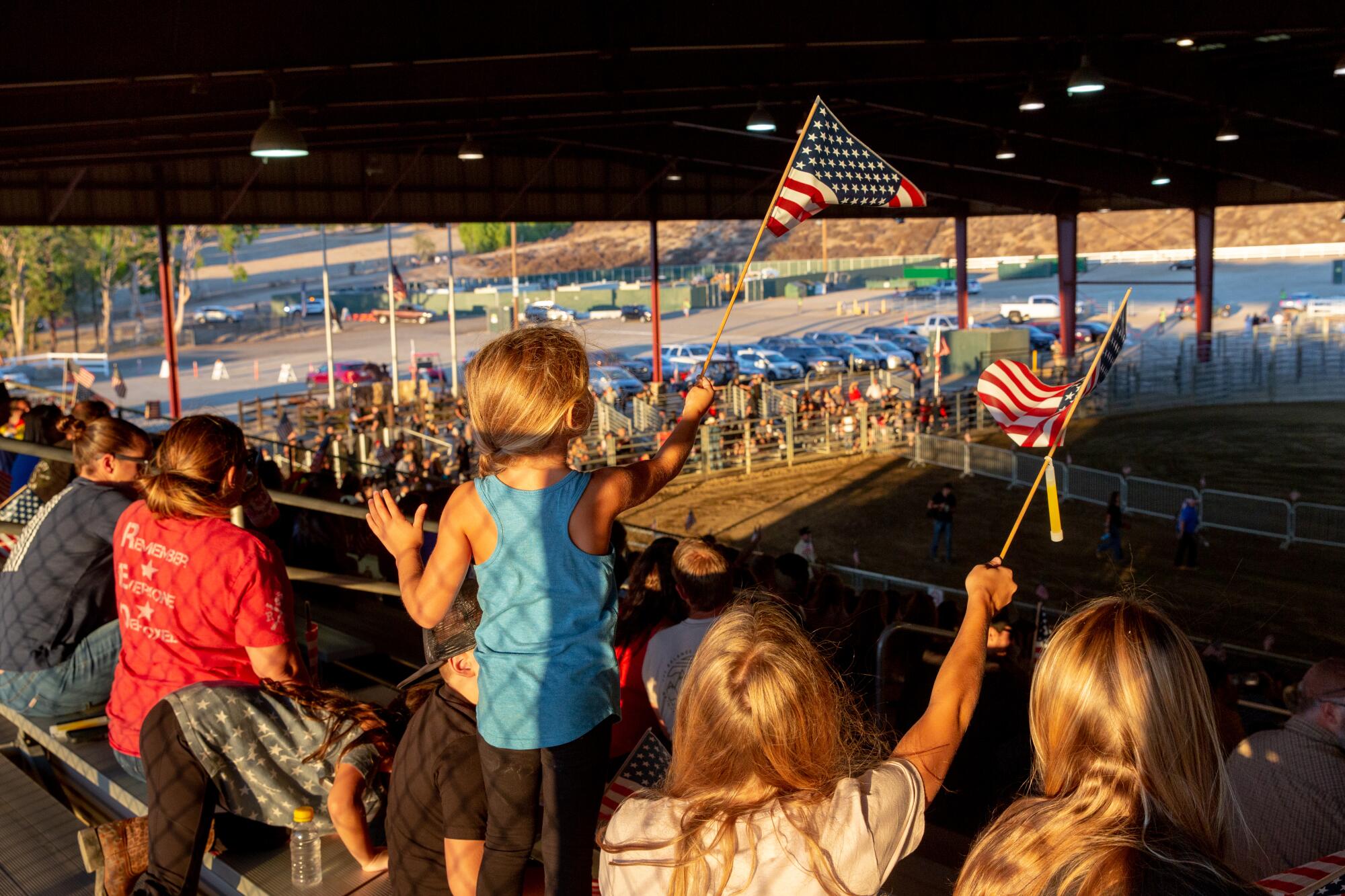 A child waves a flag with her siblings at an equestrian center