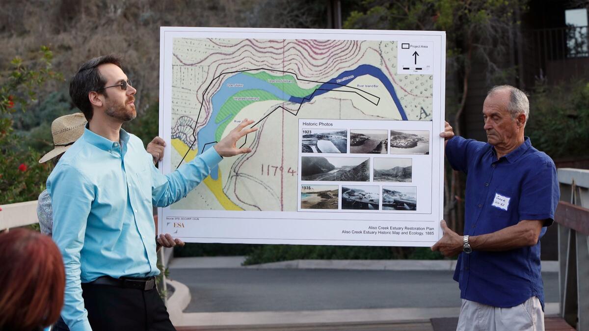 Laguna Beach resident George Weiss, right, gives hydrologist Nick Garrity a hand Thursday as Garrity discusses the Aliso Creek estuary. The Laguna Ocean Foundation hired Garrity, who's also a civil engineer, to provide expertise for a planned restoration.