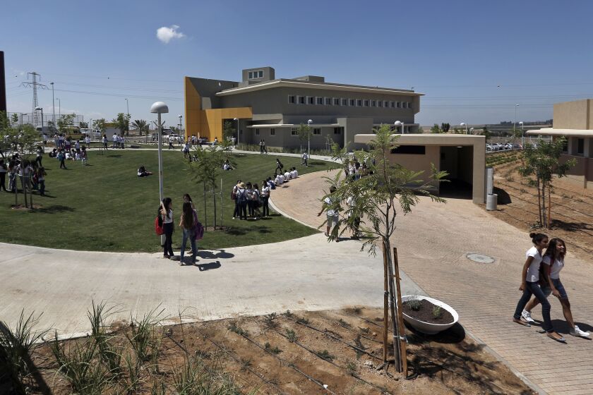 Israeli high-school students walk through the yard next to a new rocketproof school building, in Shaar Hanegev school, near the southern town of Sderot, Israel, Monday, Aug. 27, 2012. The 27.5 million US Dollar structure features concrete walls, reinforced windows and a unique architectural plan all designed specifically to absorb rocket fire.(AP Photo/Tsafrir Abayov)