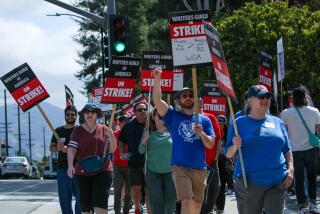 BURBANK, CA - MAY 10: A feature writer Jeremy Landers, center raised fist, and others Writers Guild of America members on strike rally in front of Disney, Burbank, CA. (Irfan Khan / Los Angeles Times)