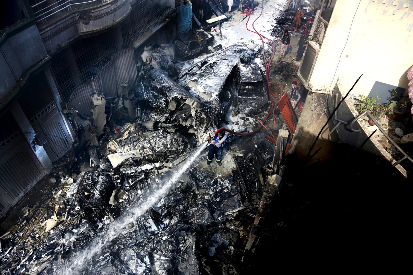 Firefighters hose down the debris caused by the crash of a Pakistani airliner in a neighborhood in Karachi on Friday.
