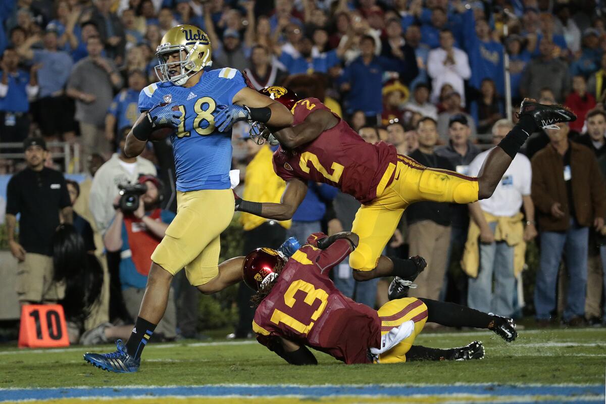 UCLA receiver Thomas Duarte slips past USC defenders Adoree' Jackson (2) and Kevon Seymour (13) on a 57-yard touchdown pass from Brett Hundley.