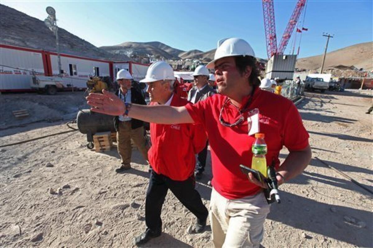 In this photo released by the Chilean government, Chile's President Sebastian Pinera, center, walks at the site of the rescue operation for 33 trapped miners at the San Jose mine near Copiapo, Chile, Tuesday Oct. 12, 2010. The first of 33 trapped miners is expected to be lifted to the surface late Tuesday after surviving more than two months below ground. (AP Photo/Hugo Infante, Chilean government)