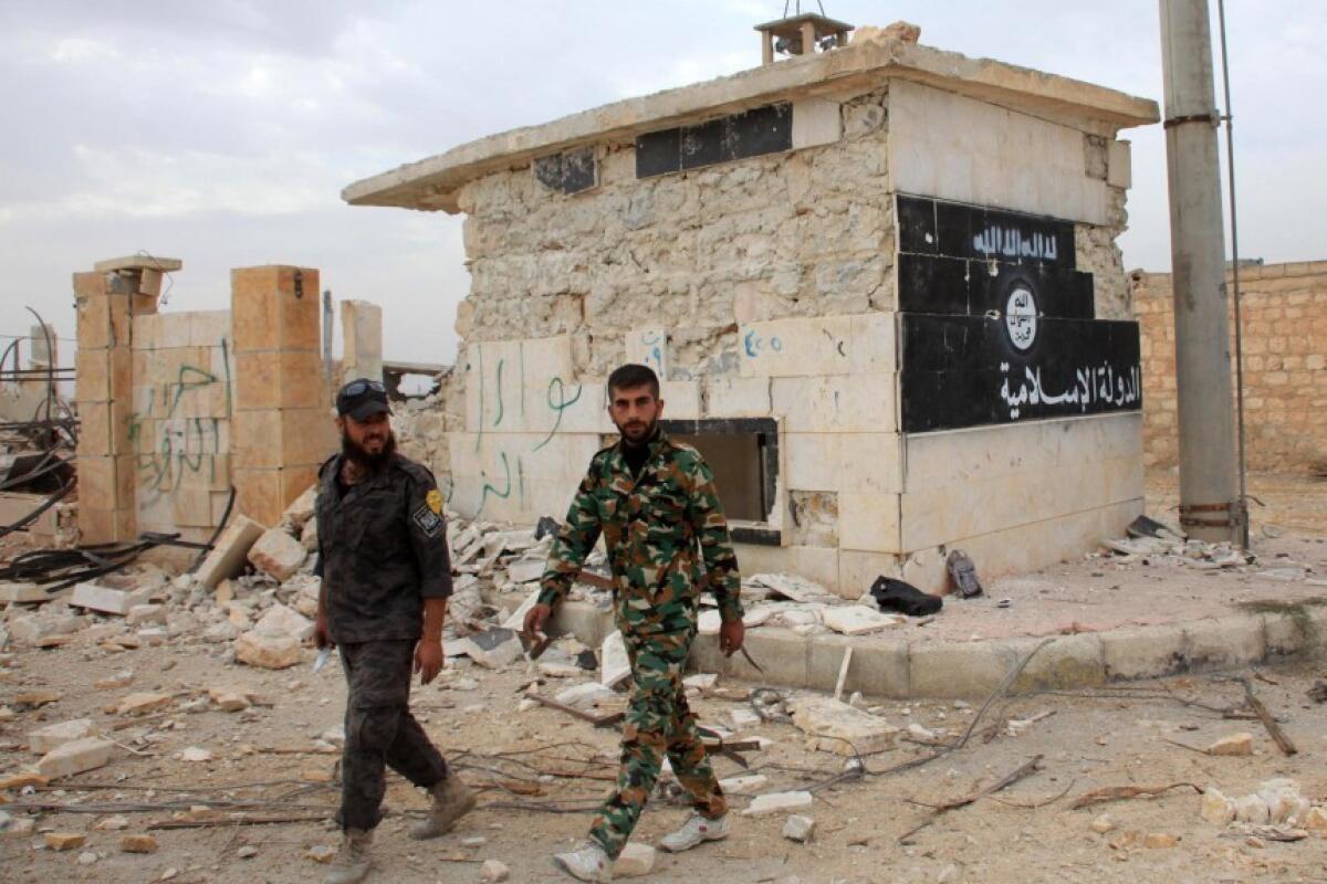 Elementos del ejército sirio caminan por una edificación que muestra la imagen de la bandera del Estado Islámico en Alepo, Siria.