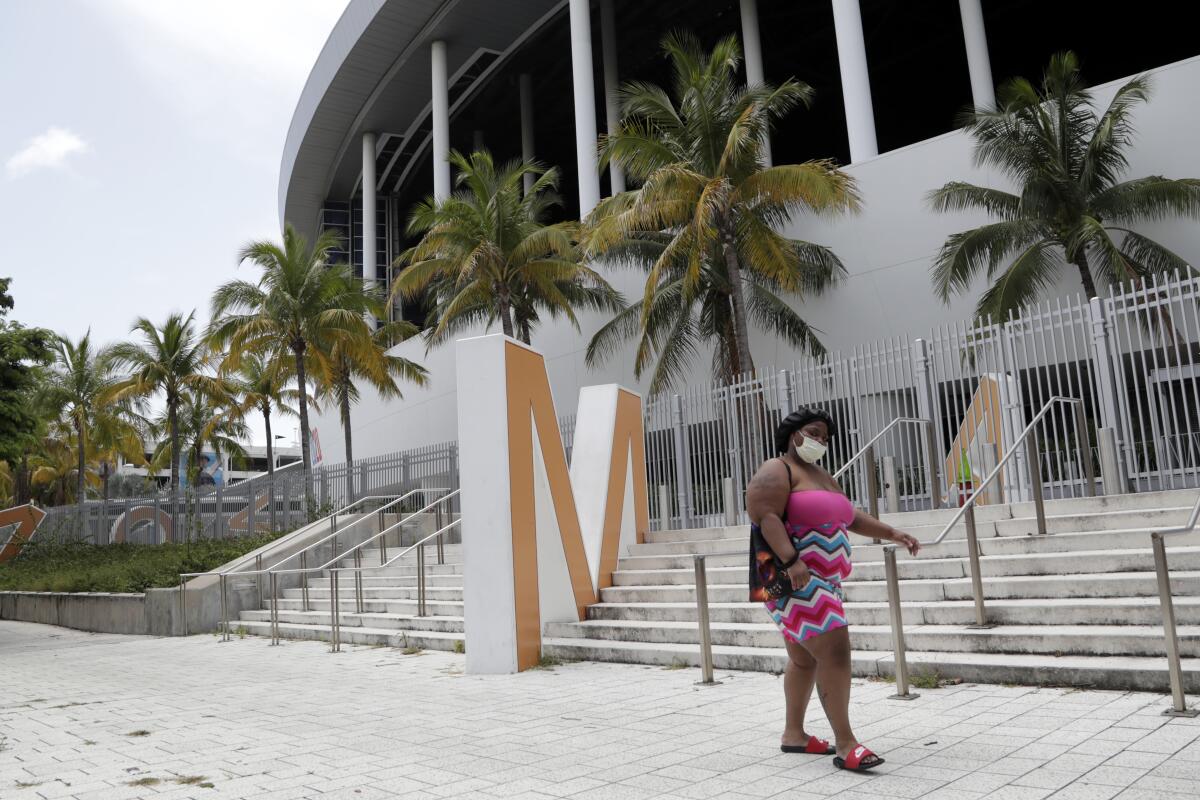 A woman wearing a protective face covering walks past Marlins Park on Monday in Miami.