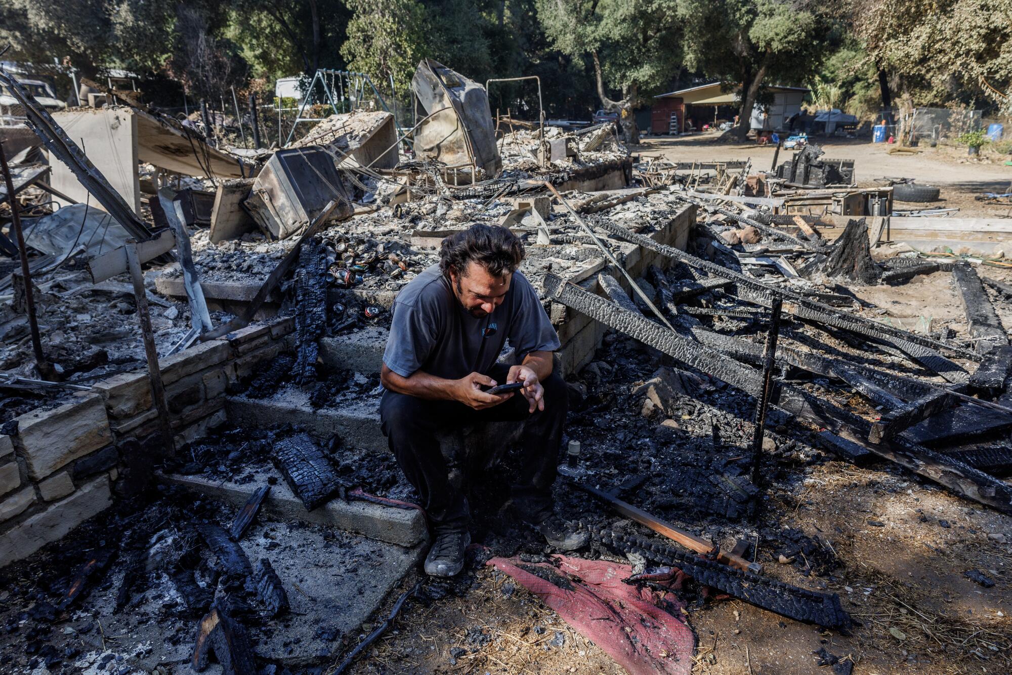 Resident Garrett Keene sits on the front steps of his home that was destroyed in the Airport fire.