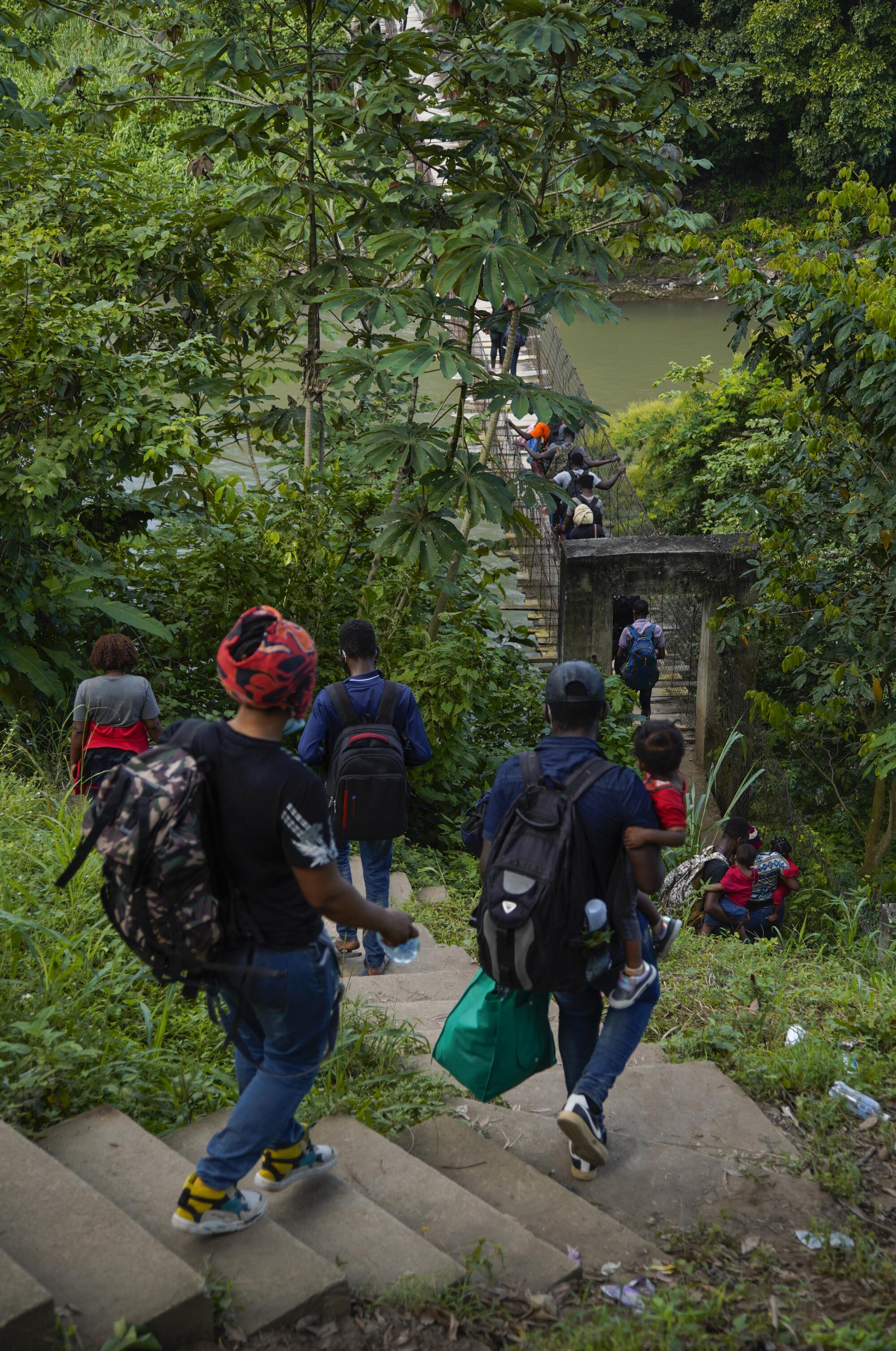 A group of Haitian migrants following smugglers' instructions cross the Cahoacán river on a rickety bridge