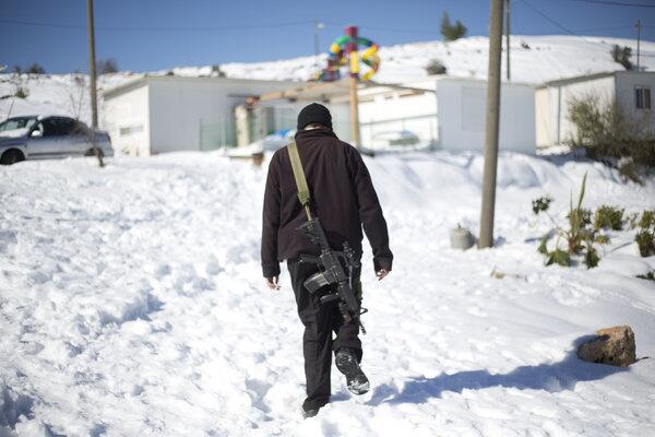 An armed Jewish settler walks in the West Bank Jewish outpost of Givat Asaf, north of the Palestinian city of Ramallah. A blustery storm, dubbed Alexa, has brought gusty winds, torrential rains and heavy snowfall to parts of the Middle East.
