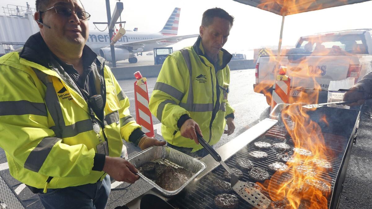 Airport workers flip burgers and hot dogs on a grill set up on a tarmac at Salt Lake City International Airport on Wednesday as part of a lunch for government workers not getting paid during the shutdown.