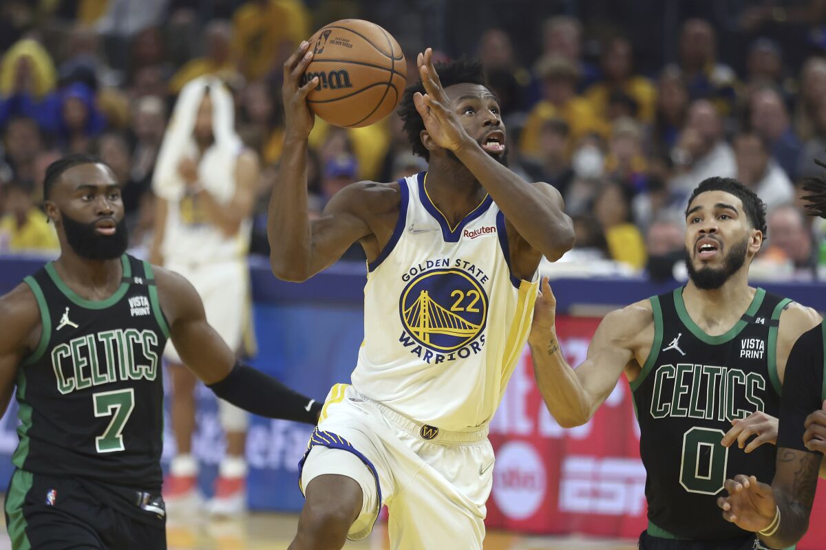Golden State Warriors forward Andrew Wiggins shoots against Boston Celtics guard Jaylen Brown and forward Jayson Tatum.