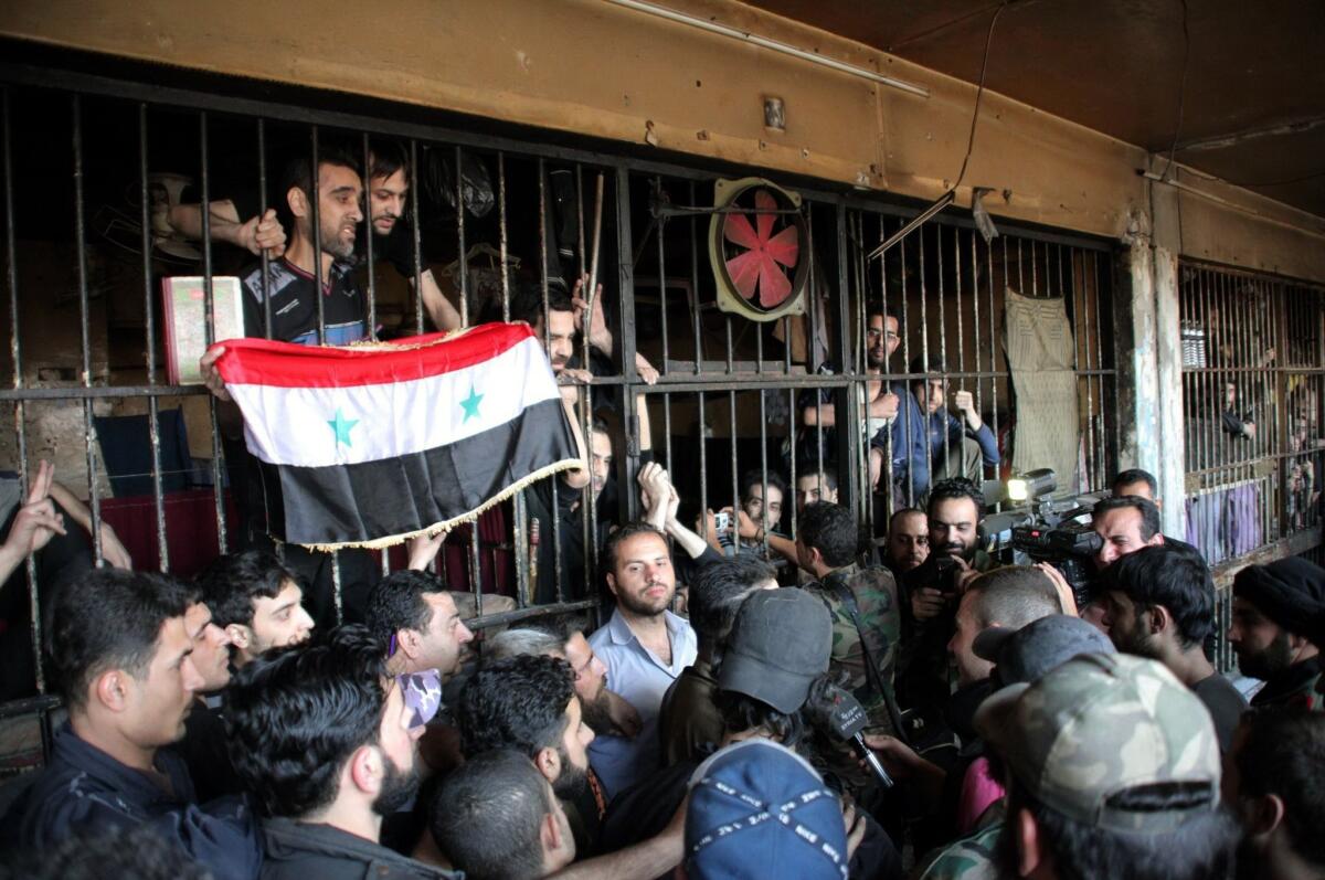 An image released by the official Syrian news agency is said to show inmates holding the national flag after pro-government forces broke a siege of the main prison in Aleppo.