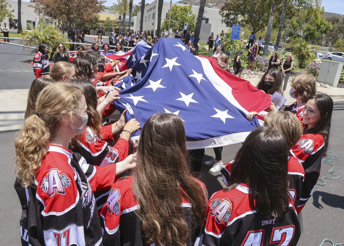 Members of the San Diego Angels hockey team take down an American flag after the memorial service.