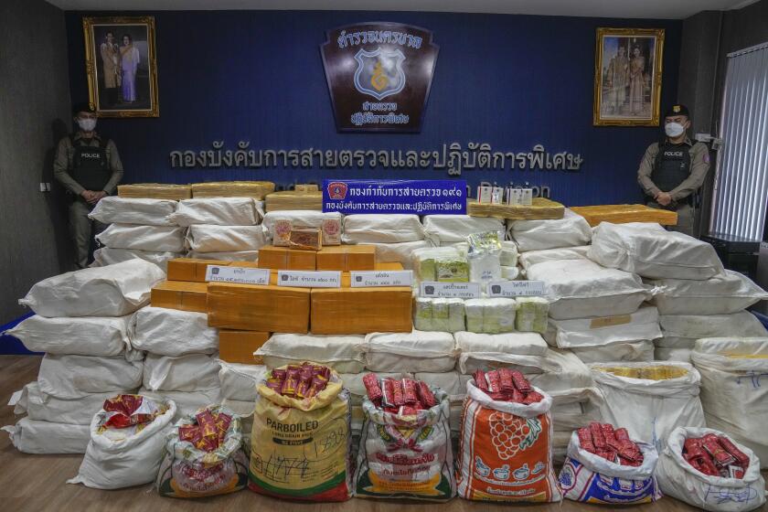 ARCHIVO - Agentes de policía tailandeses de pie detrás de los paquetes que contienen metanfetamina y heroína incautados durante una conferencia de prensa Bangkok, Tailandia, el 28 de septiembre de 2023. (AP Foto/Sakchai Lalit)