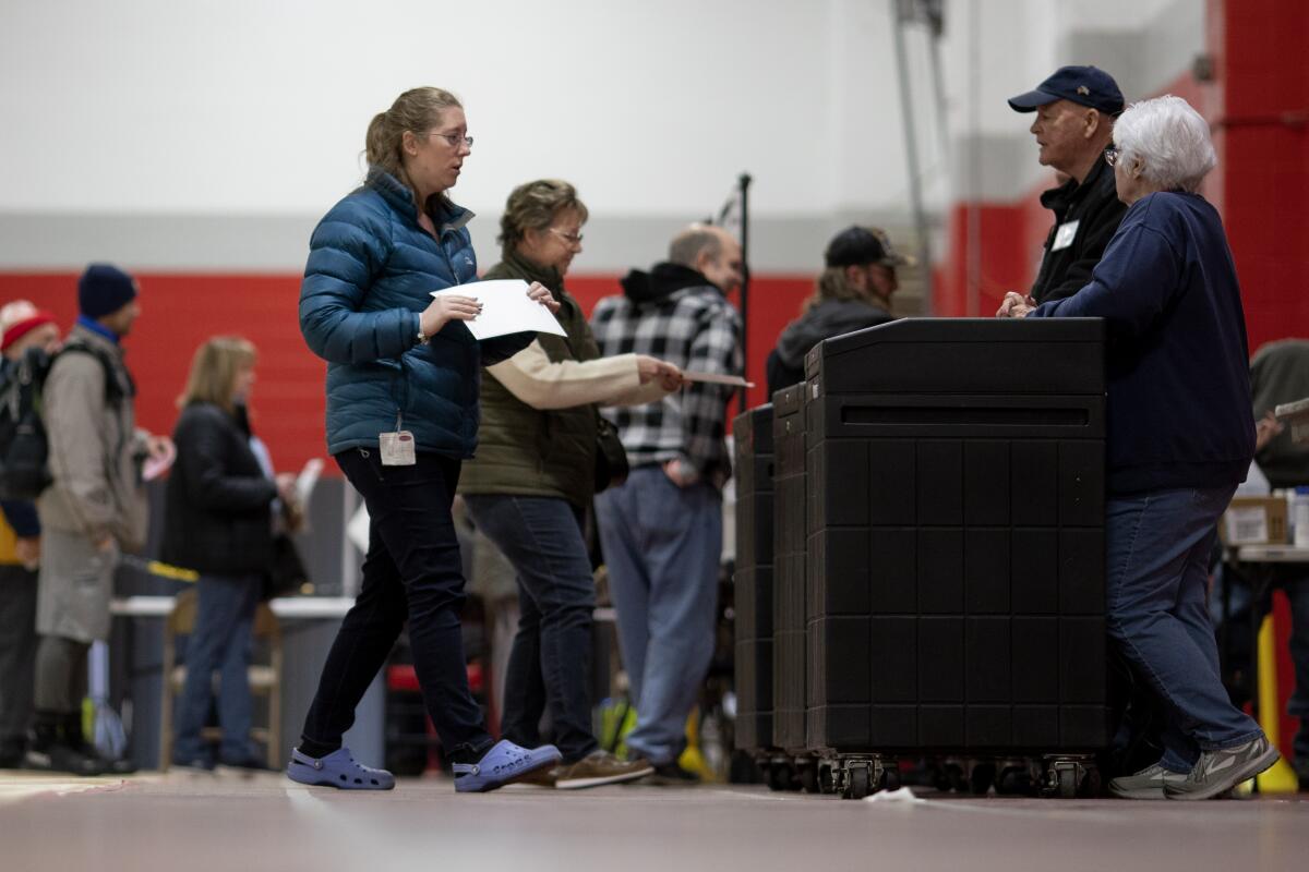 A voter holding a ballot walks toward a machine at a polling site.