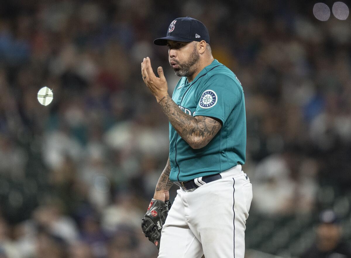 Seattle Mariners relief pitcher Hector Santiago blows on his hand between pitches during the eighth inning of the team's baseball game against the Texas Rangers, Friday, July 2, 2021, in Seattle. (AP Photo/Stephen Brashear)