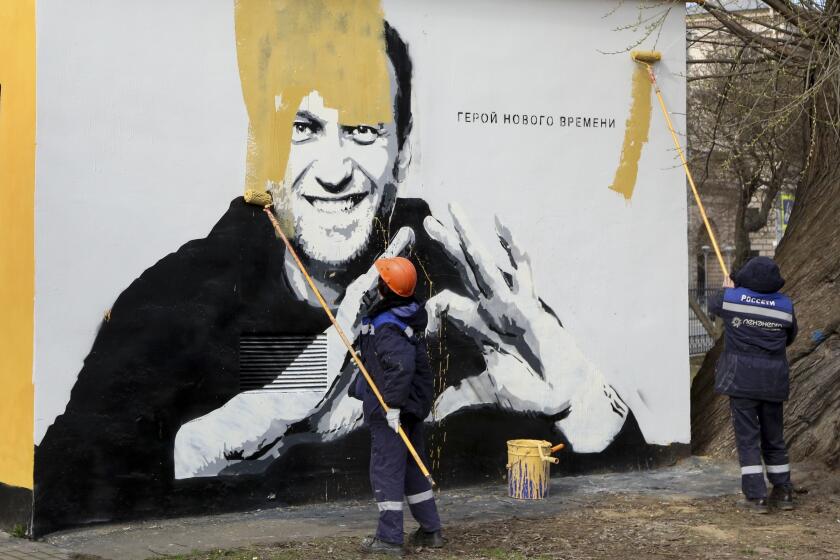 FILE - In this April 28, 2021, file photo, municipal workers paint over an image of Russia's imprisoned opposition leader Alexei Navalny with the words reading "Hero of our time" in St. Petersburg, Russia. Russia is holding three days of voting and there's no expectation that United Russia, the party devoted to President Vladimir Putin, will lose its dominance in the State Duma. The main question is whether the party will retain its two-thirds majority that allows it to amend the constitution. Another question is whether the Smart Voting strategy devised by Navalny will prove viable against United Russia. (AP Photo/Valentin Egorshin, File)