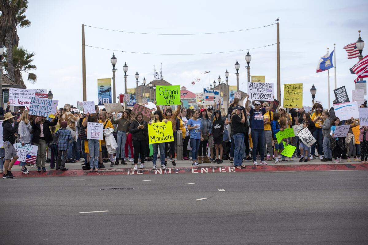 Hundreds of people gather on Pacific Coast Highway near the Huntington Beach Pier to protest vaccination mandates on Monday.