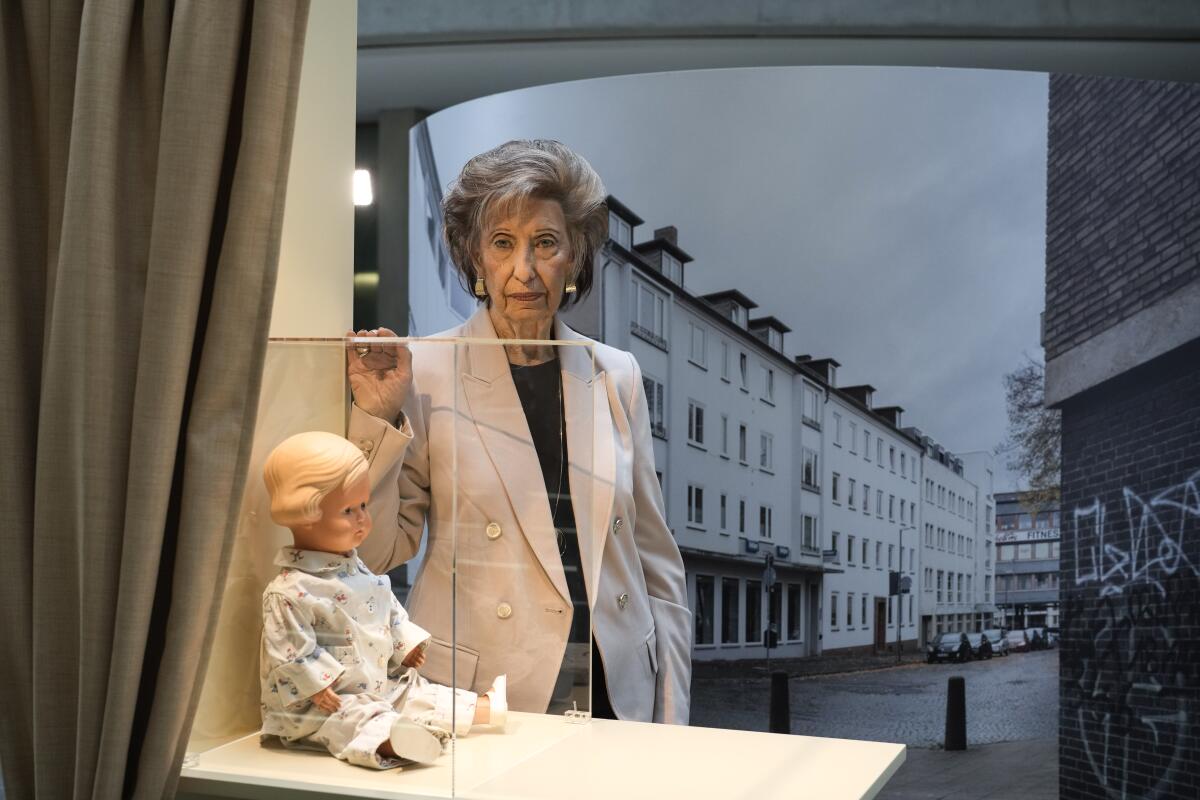 Holocaust survivor Lore Mayerfeld poses next to her doll Inge as part of an exhibition.