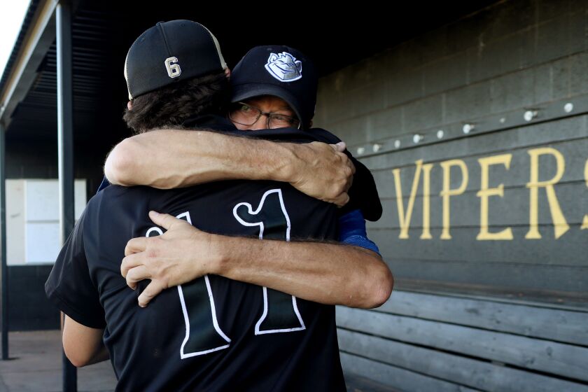 BUCKEYE, ARIZ. -- FRIDAY, MAY 10, 2019: Tanner Spallina, 17, a catcher on the Verrado High School baseball team gives Daryl McKinsey, right, father of deceased player Bryan Mckinsey, a hug while teammate Rocky King, 19, looks on at the school in Buckeye, Ariz., on May 10, 2019. Bryan McKinsey, 17, a junior Verrado High School baseball player, died May 9, 2018, of a fentanyl overdose, in Buckeye, Ariz. McKinsey, was found unresponsive at home in Buckeye. A small baggie containing blue pills and aluminum foil were found in his wallet. He is survived by parents Daryl and Melissa McKinsey and brother Parker, 21. (Gary Coronado / Los Angeles Times)
