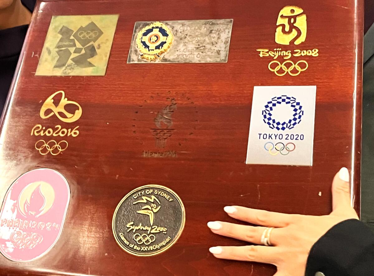 Delta flight attendants display a briefcase that holds the Olympic flag. It has stickers from past Olympic host cities.