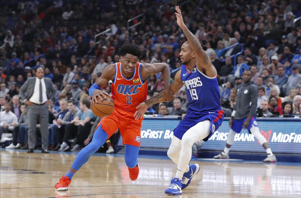 Oklahoma City Thunder guard Shai Gilgeous-Alexander drives around Clippers guard Rodney McGruder.