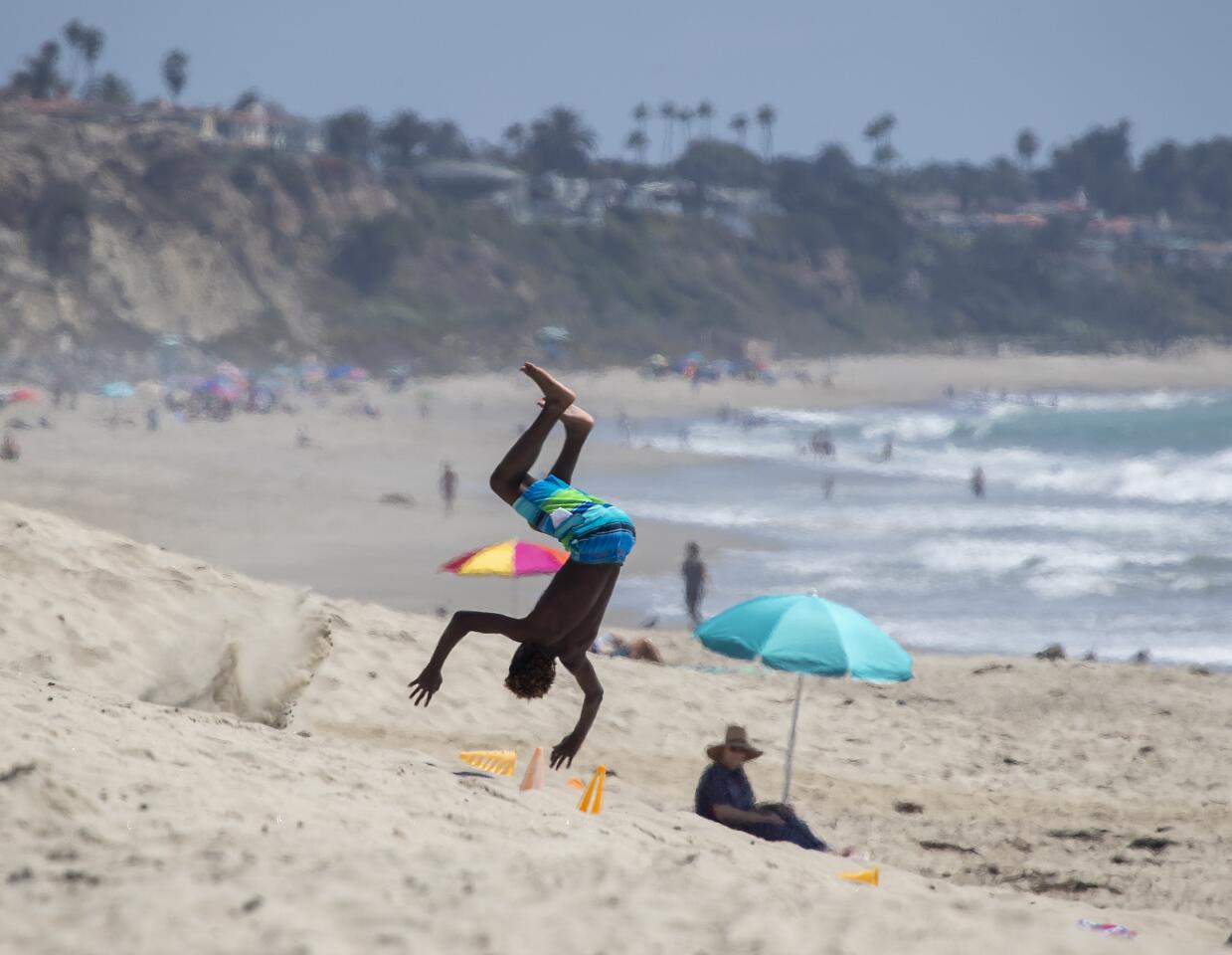 A youngster does a flip on the beach near the San Clemente Pier