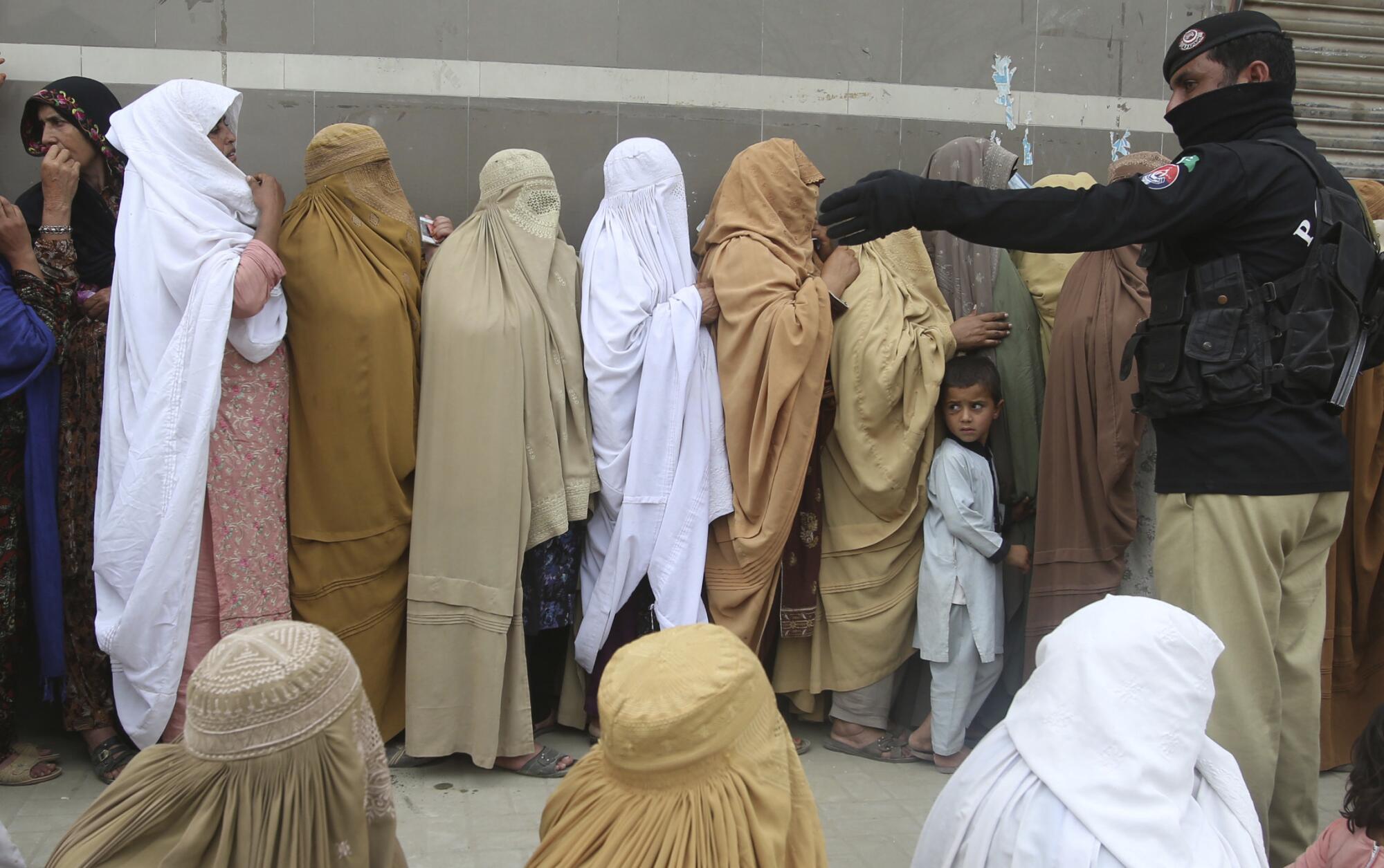 Women wait in line to receive cash under a government relief program in Peshawar, Pakistan, in April.