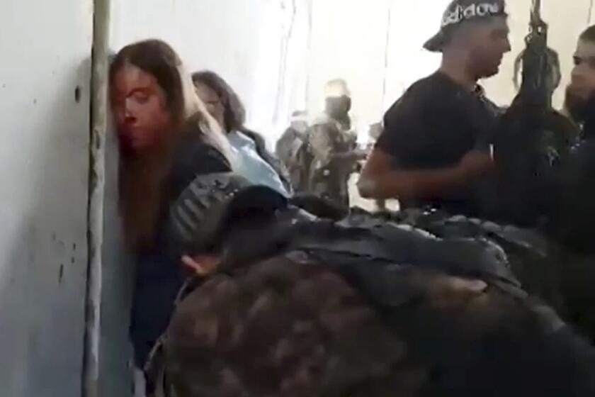 In this image taken from video provided by the Hostage Families Forum, Israeli female soldiers from the Nahal Oz military base are placed against the wall and shackled by members of Hamas after they were taken captive on Oct. 7, 2023. The footage was taken by Hamas militants who stormed the Nahal Oz military base, part of the militant group’s wider assault on southern Israel that killed roughly 1,200 people and took about 250 others hostage. (Hostage Families Forum via AP)