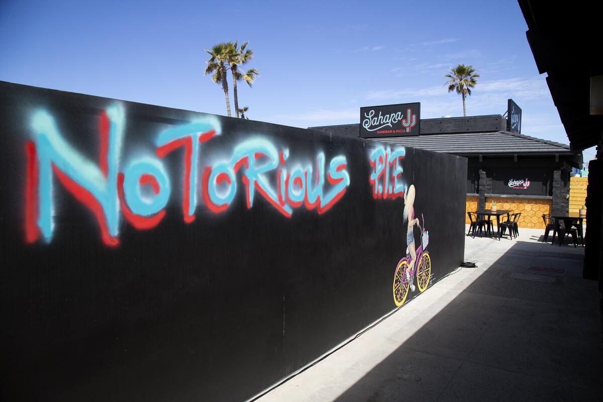 A wall by the restrooms is decorated with art that reads "Notorious P.I.E." at Sahara Sandbar & Pizza in Huntington Beach.