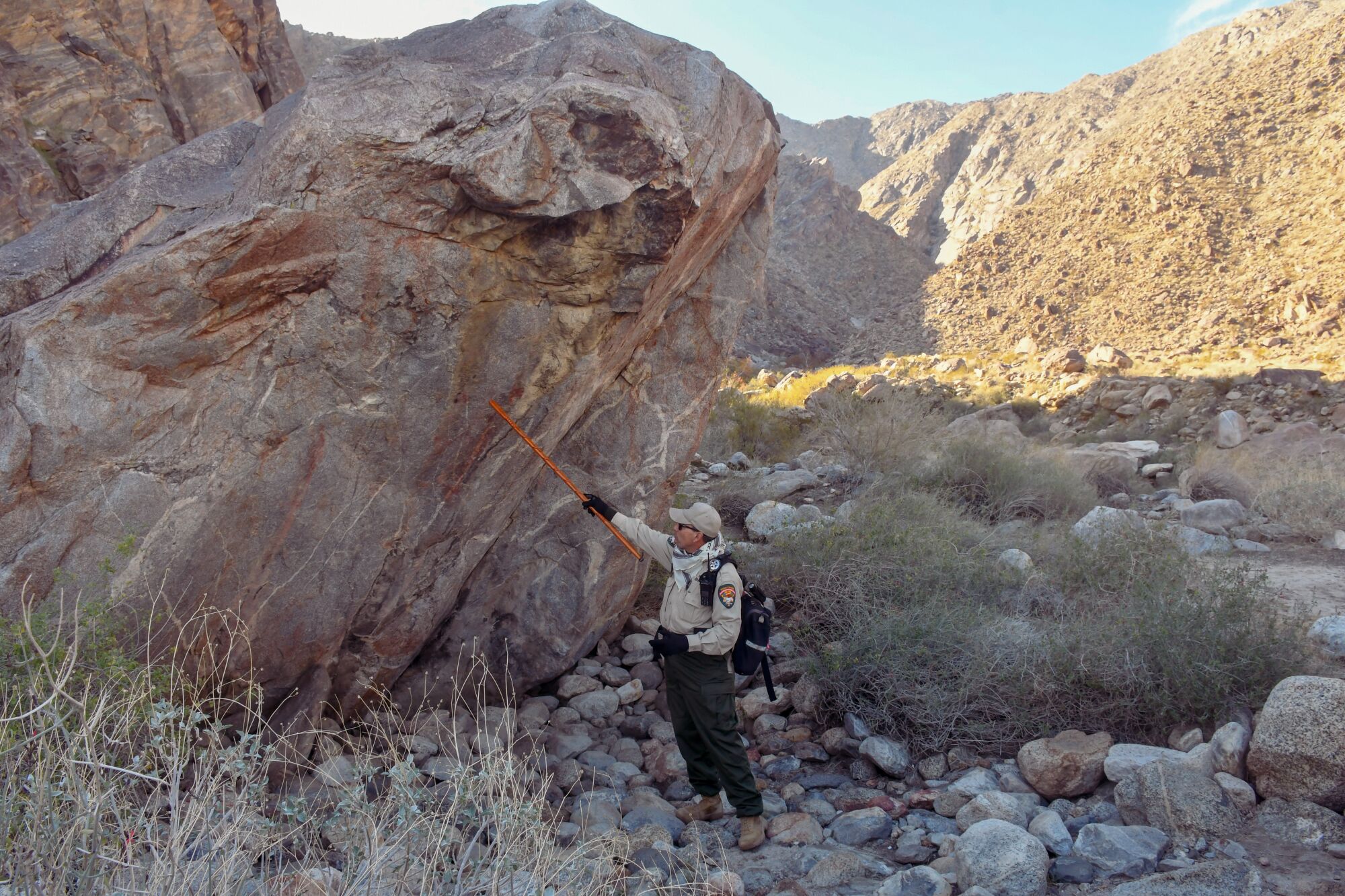 A ranger points at a large rock.