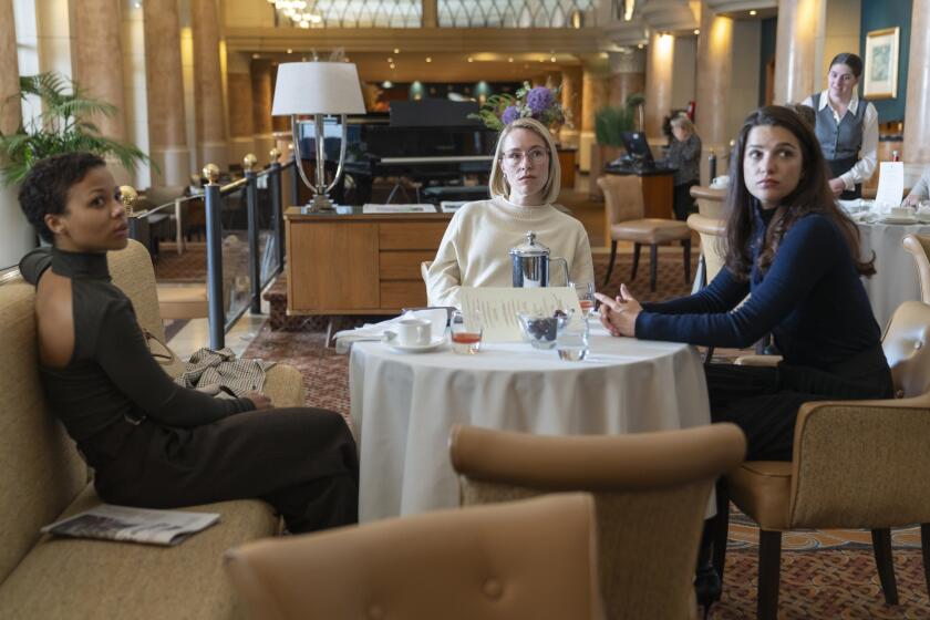 Three women look up from a table at breakfast.