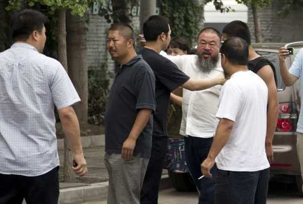 Ai Weiwei, third from right in the white, button-down shirt, argues with a policeman, center, outside his home in Beijing on Wednesday.