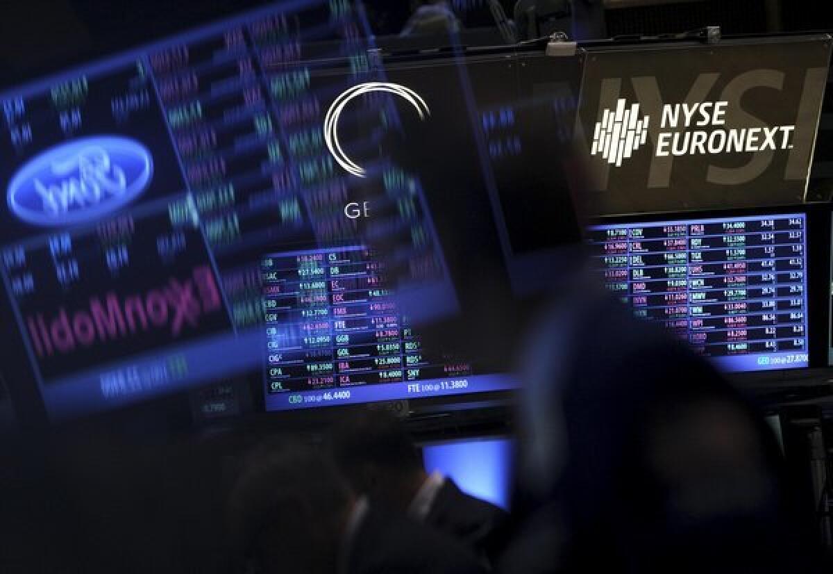 Traders are reflected in monitors showing stock quotes at the New York Stock Exchange.