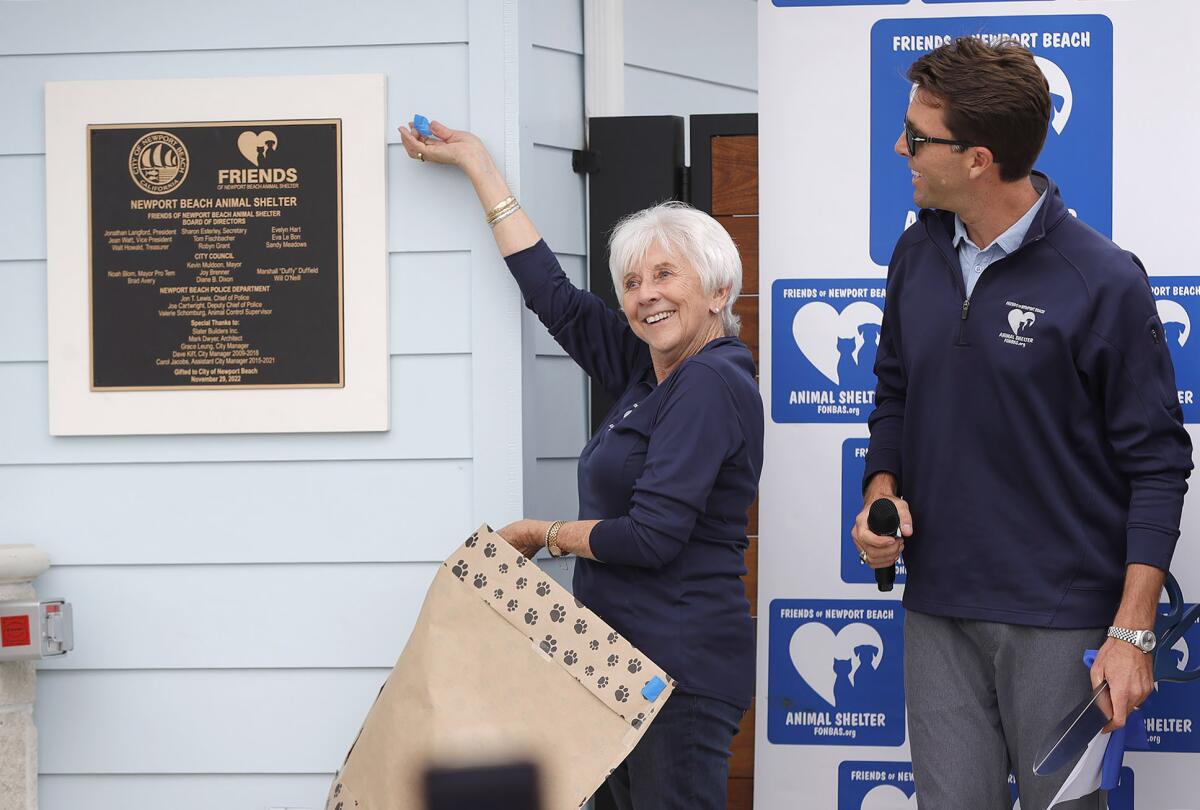 Secretary Sharon Esterley and President Jon Langford unveil a ceremonial wall plaque.