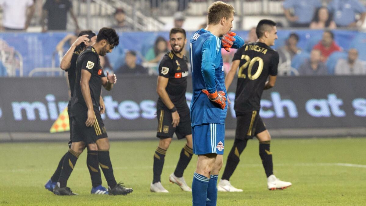 Toronto FC goalkeeper Clint Irwin reacts as LAFC's Carlos Vela, left, is congratulated after scoring his team's fourth goal.