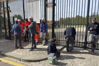 Workers wait outside the gate at The Palace of Versailles on Tuesday, Oct. 17, 2023 in Versailles, France. One of France's most visited tourist attractions, was evacuated for a security scare, for the the second time in four days, with France on heightened alert against feared attacks after the fatal stabbing of a school teacher. (AP Photo/Pat Eaton-Robb)