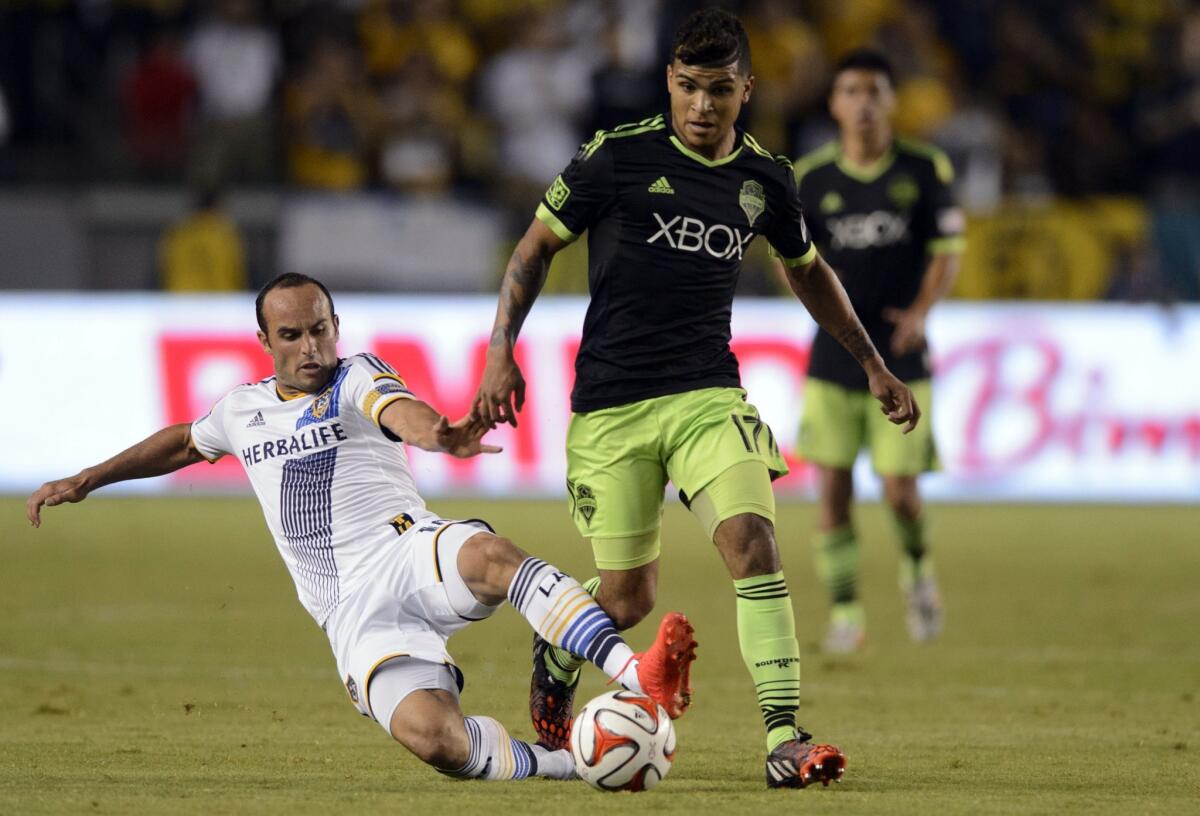Landon Donovan slides for the ball as Seattle's DeAndre Yedlin moves down the field during a match on Oct. 19.