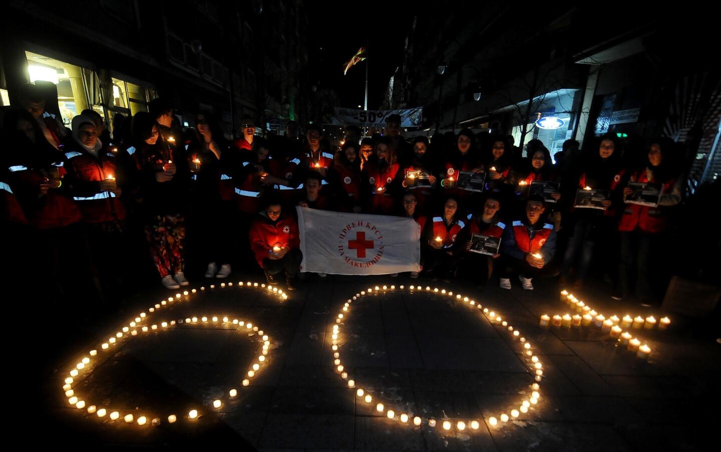 Activists of the Red Cross gather in front of lit candles forming the number "60" during "Earth Hour" in Skopje's main square on March 28, 2015.
