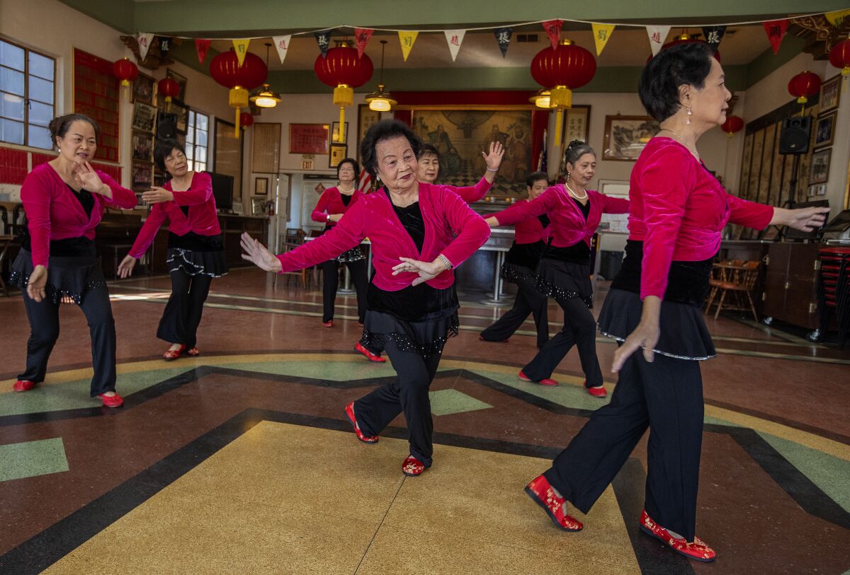 A group of women in matching red and black uniforms dance.