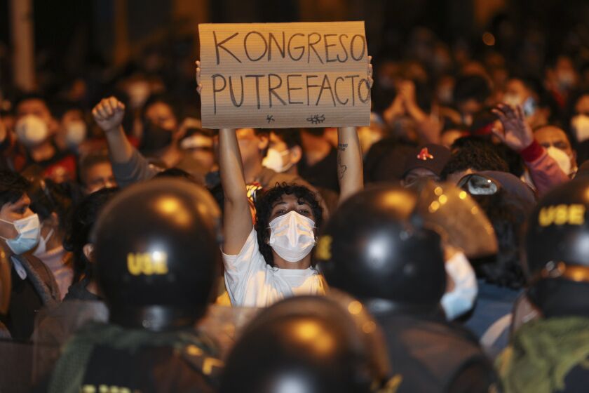 A man holds a sign reading in Spanish "Rotten Congress" during a protest against Congress decision to oust President Martin Vizcarra in Lima, Peru, Monday, Nov. 9, 2020. Peruvian lawmakers voted overwhelmingly Monday night to remove Vizcarra from office, expressing anger over his handling of the coronavirus pandemic and citing alleged but unproven corruption allegations. (AP Photo/Martin Mejia)