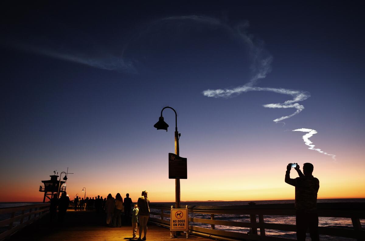 A contrail from a rocket launch in the dusk sky.