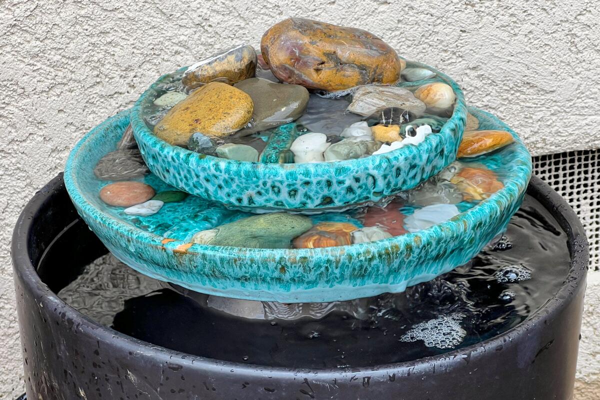 Pools of water flow from a rocky platter into a recycled planter.