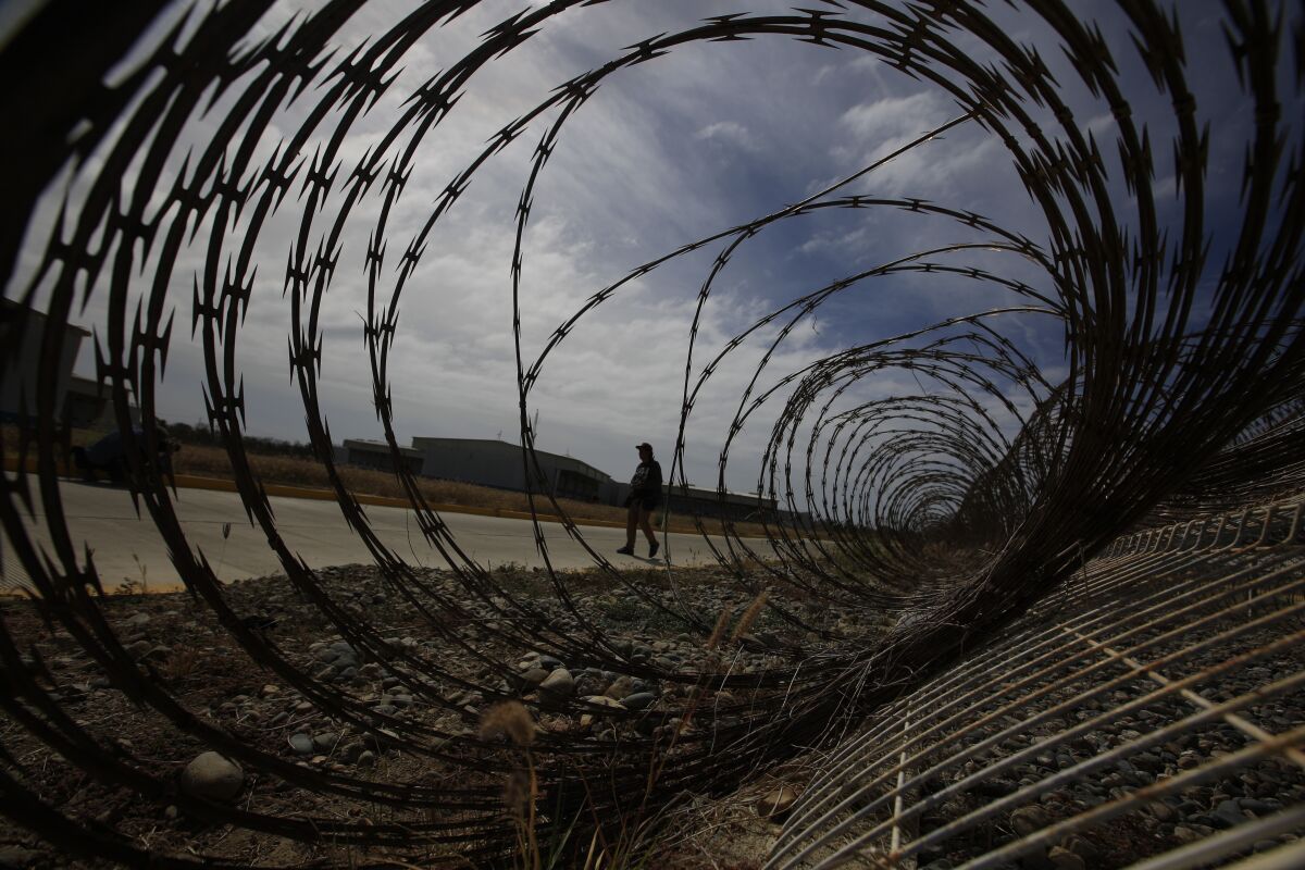 FILE - A journalist walks past a fallen section of fencing during a media tour of the now closed Laguna del Toro maximum security facility on the former Islas Marias penal colony located off Mexico's Pacific coast, Saturday, March 16, 2019. President Andrés Manuel López Obrador had the facility converted into an environmental education center. Now the government wants to make it an ecotourism destination where visitors can watch sea birds and enjoy the beaches. (AP Photo/Rebecca Blackwell, File)