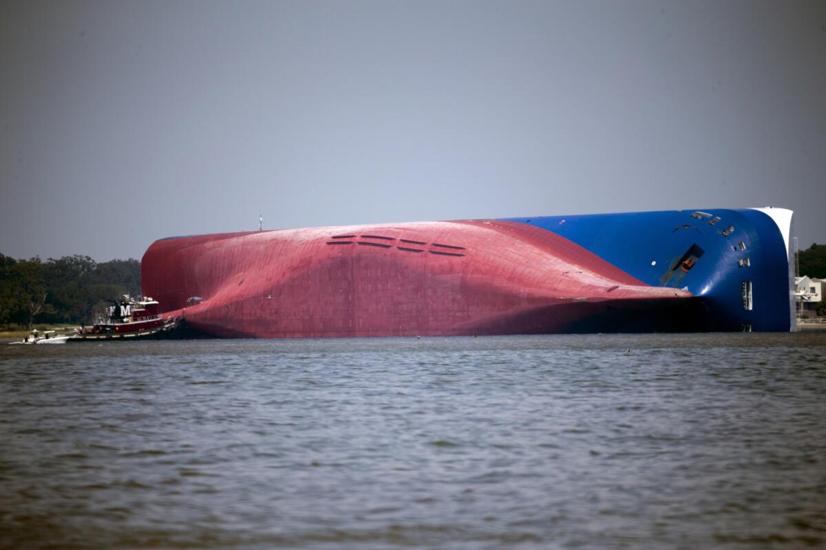 A large cargo ship capsized on its side in the water