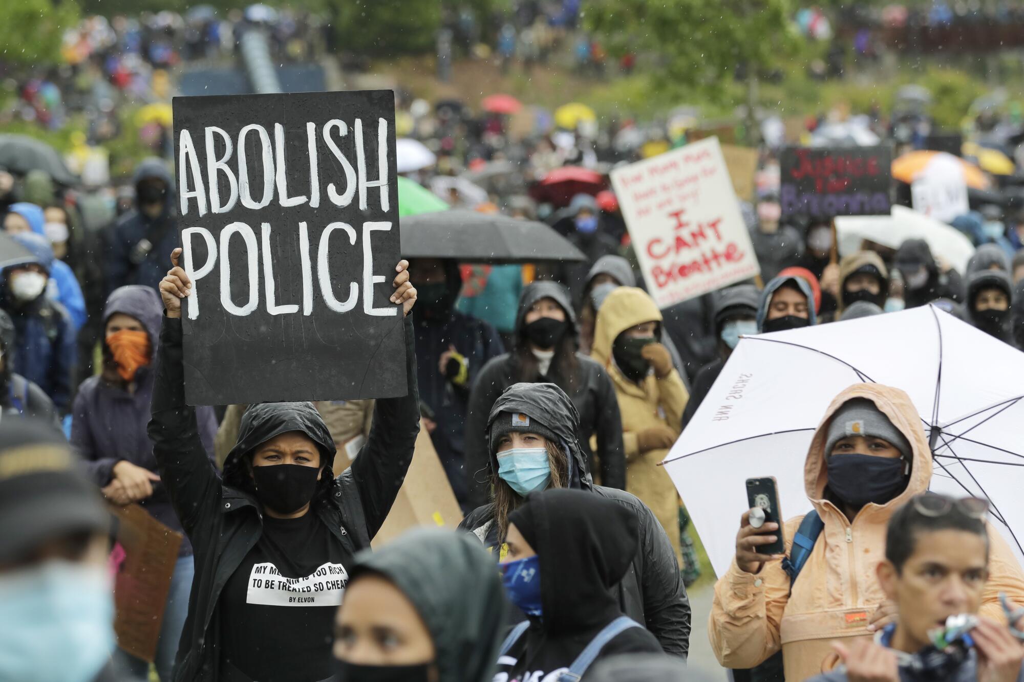 A protester holds a sign that reads "Abolish Police."