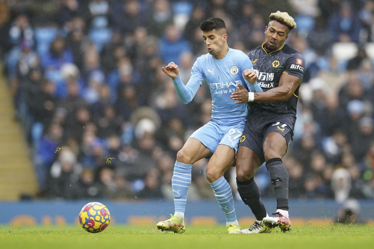 El portugués Joao Cancelo, del Manchester City, disputa un balón con Adama Traore de Wolverhampton.